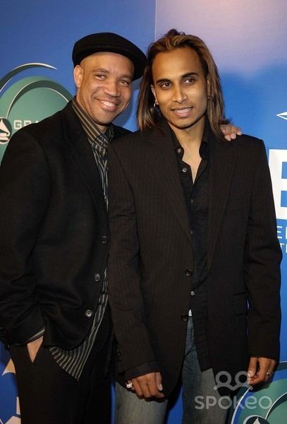 Kerry Gordy smiling and wearing a black coat and black and gray striped long sleeves while Reggie Benjamin wearing black coat and long sleeves