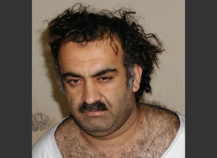 Khalid Sheikh Mohammed with mustache and hairy chest while wearing a white t-shirt