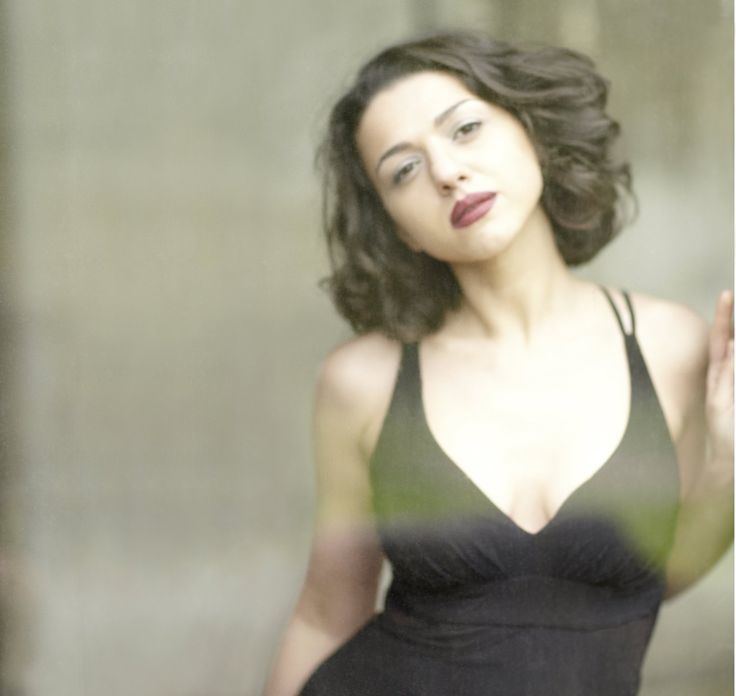 Khatia Buniatishvili posing with her hair freely flowing and wearing a black sleeveless dress.