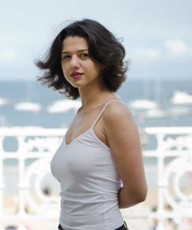 Khatia Buniatishvili posing with her hair slightly windswept and wearing a white sleeveless shirt.