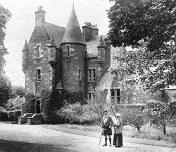 An old photograph of Kilberry Castle with two persons beside it