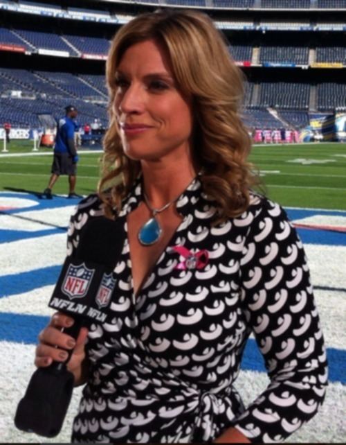 Kim Jones conducting an interview after a football game and wearing a black and white dress along with a blue necklace.