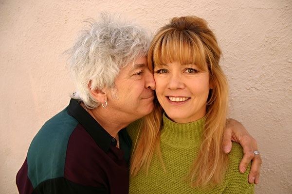 Kim McLagan smiling with her husband Ian Mclagan embracing and kissing her