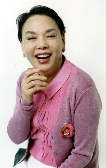 Kim Soo-mi laughing and wearing a pink blouse and a blazer.