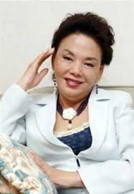 Kim Soo-mi smiling and wearing earrings, a necklace, and a white blazer.