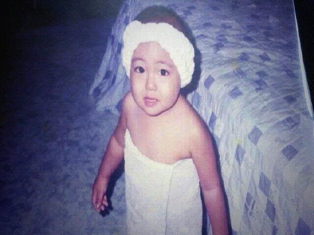 Baby Kim Taehyung smiling, wearing a white headband and white towel.