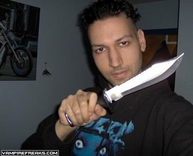 Kimveer Gill holding a dagger while wearing a black and blue sweatshirt