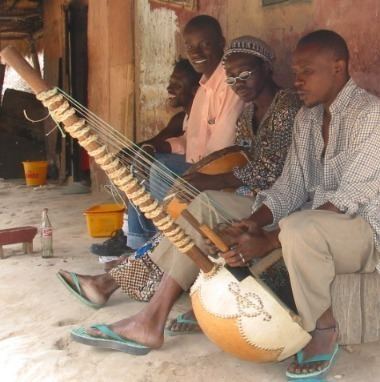 A man playing Kora with people looking at him.