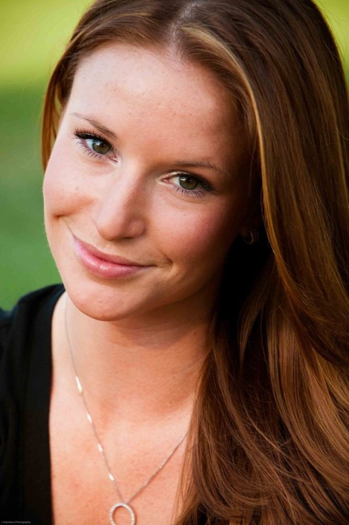 Kristin Fisher with a smiling face, wearing a necklace and a black shirt.