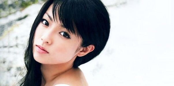 Kyoko Fukada with an innocent face, black hair, and side bangs while wearing a white sleeveless blouse