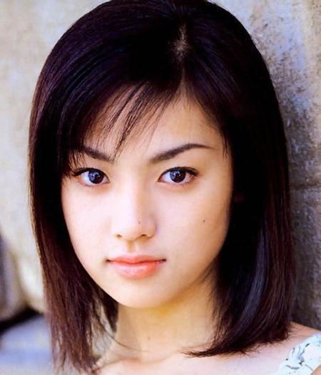 Kyoko Fukada with a serious face, black shoulder-length hair, and side bangs while wearing a sleeveless blouse