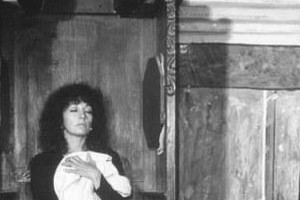 Isela Vega as Matea kneeling inside a church and holding a white priest outfit and wearing a black dress in a scene from La Viuda Negra, 1977.