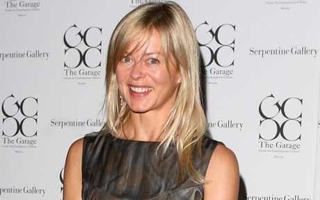 Helen Taylor at the Serpentine Gallery Summer Party is smiling, has blonde hair, and wears silver earrings, and a dark gray dress with a design.