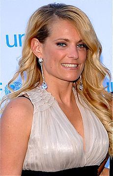 Laila Bagge smiles while wearing a white dress and long earrings