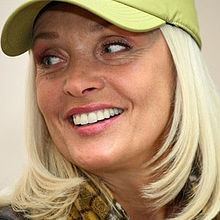 Laima Vaikule smiling with a blonde hair and wearing a green cap