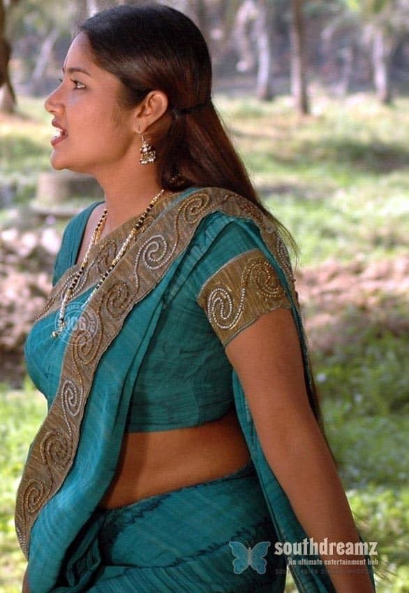 Lakshana talking to someone while wearing a blue and brown dress, dupatta, necklace, and earrings
