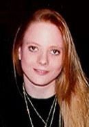 Lana M. Tisdel smiling, with long blonde hair, wearing necklaces and a black shirt.