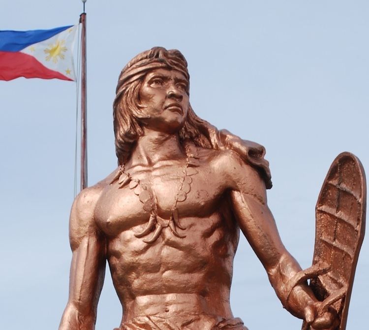 Close-up shot of flag of the Philippines and the bronze monument of Lapu-lapu
