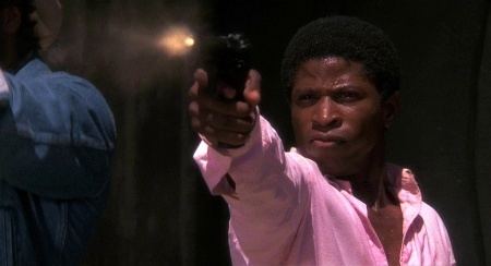 Larry B. Scott while firing a gun wearing a pink long-sleeved shirt