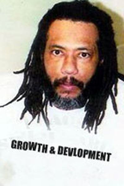 Larry Hoover with braided hair, mustache, and beard while wearing a white sweatshirt