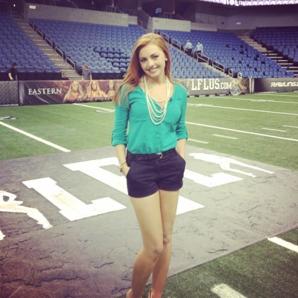 Lauren Gardner smiling while wearing blue-green long sleeves, necklace, and black shorts