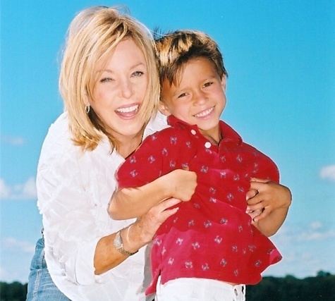 Lauren Manning smiling while carrying her son wearing a red polo shirt
