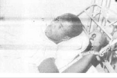 Lawrence Anini lying on the bed with handcuffs
