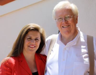 Leda Cosmides smiling while wearing a red blazer and John Tooby wearing white long sleeves and eyeglasses