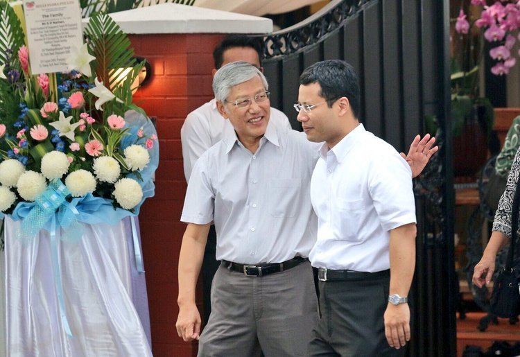 Lee Yock Suan smiling and wearing eyeglasses and a polo shirt with  Desmond Lee wearing eyeglasses and a white polo shirt.