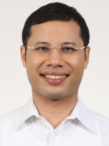 Desmond Lee with a smiling face, wearing eyeglasses and a white polo shirt.