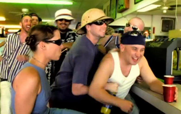 Marc Costanzo wearing a blue cap and a white sleeveless shirt and Sharon Costanzo wearing sunglasses and a sleeveless top with a group of people having fun.