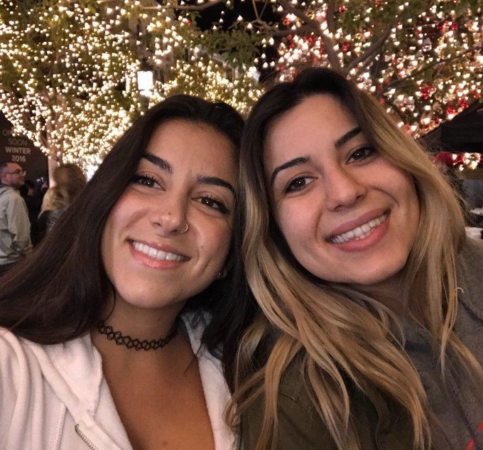 Lena The Plug smiling with her sister Paulina Nersesian. Lena wearing a white jacket and black chocker while her sister wearing a gray jacket.