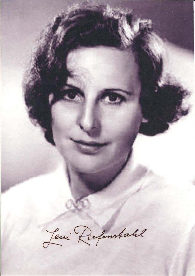 Leni Riefenstahl smiling, with wavy short hair and wearing a white shirt.