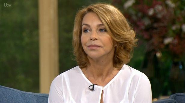 Leslie Ash sitting on a sofa while wearing a white sleeve