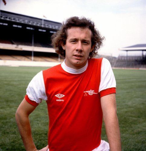 Liam Brady with wavy hair and wearing a red and white shirt.