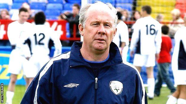 Liam Brady with a serious face and wearing a blue jacket.