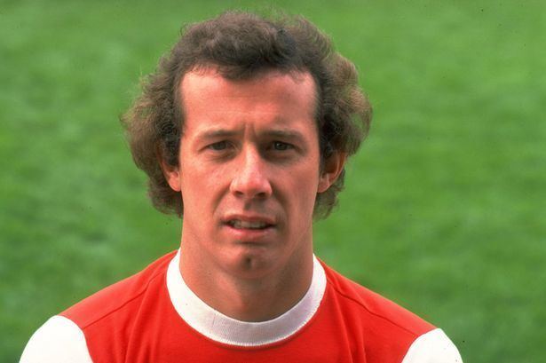 Liam Brady with messy hair and wearing a red and white shirt.