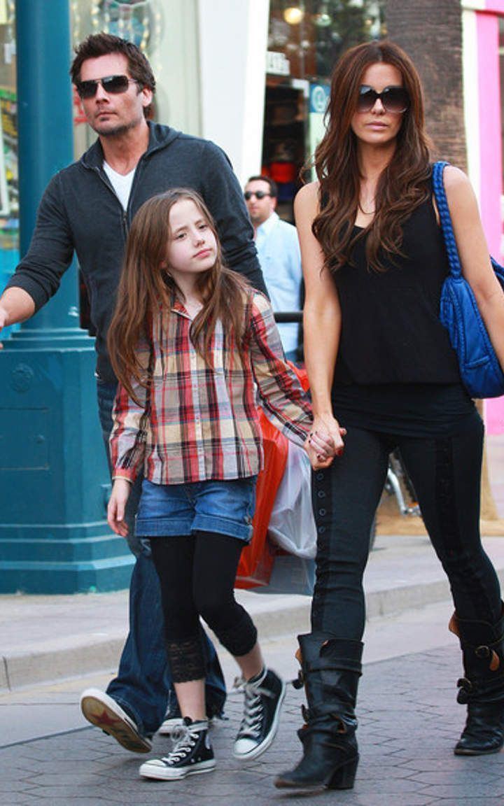 Len Wiseman, Lily Mo Sheen, and Kate Beckinsale walking hand in hand while Lily wearing a checkered long sleeve blouse, shorts, and leggings
