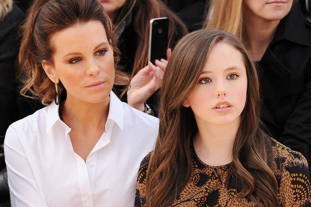 Kate Beckinsale and Lily Mo Sheen looking at something while her mother, Kate is wearing a white dress and Lily wearing a black and brown dress