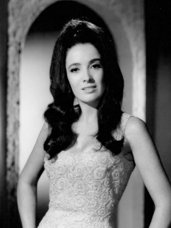 Linda Cristal smiling while wearing a sleeveless dress with a circle pattern