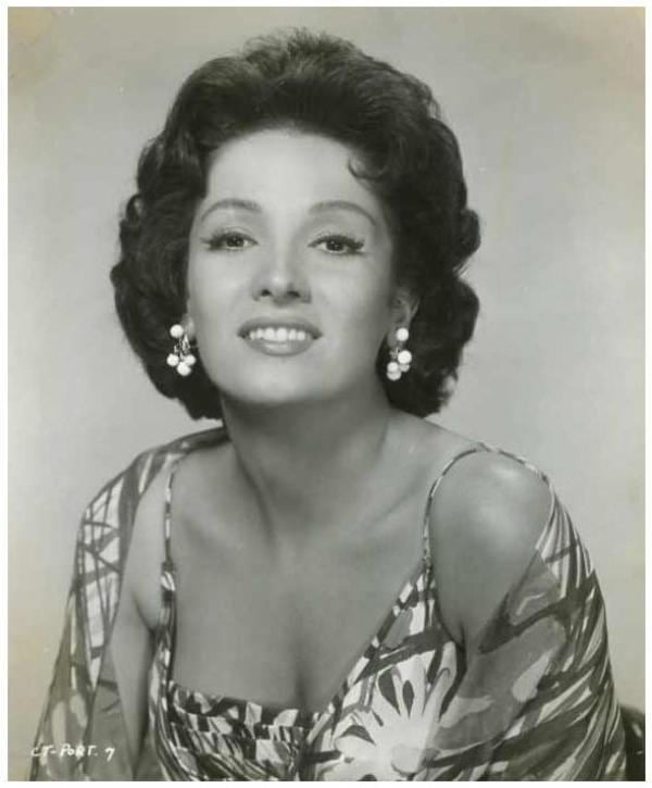 Linda Cristal smiling while wearing a sleeveless blouse paired with a shawl and earrings