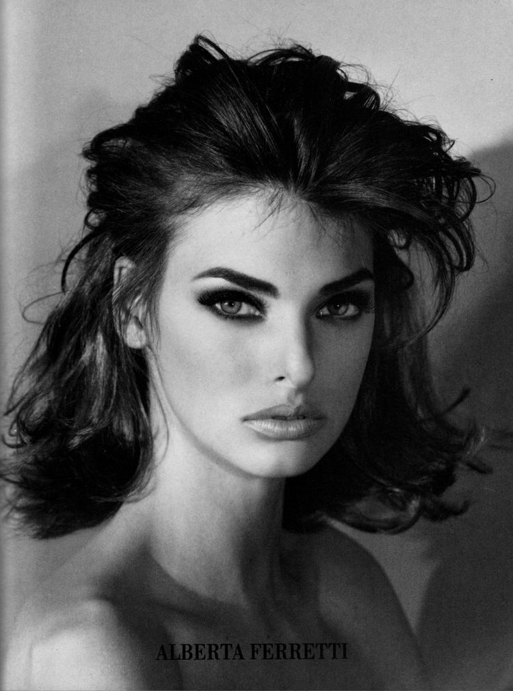 Linda Evangelista with a fierce look and black shoulder-length hair while being topless