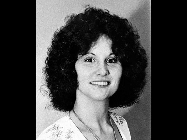 Linda Lovelace smiling, with curly black hair, wearing a necklace and a white floral top.