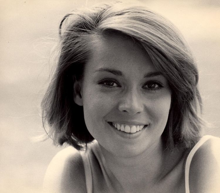 Linda Miller with a smiling face, short hair, and wearing a white top.