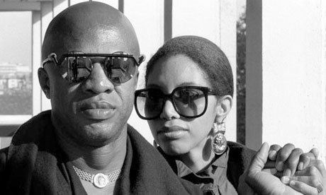 Cecil Womack looking fierce with his wife Linda Womack and holding hands together while wearing coats and shades
