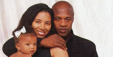 Linda Womack smiling while embraced from behind by his husband Cecil Womack together with their child