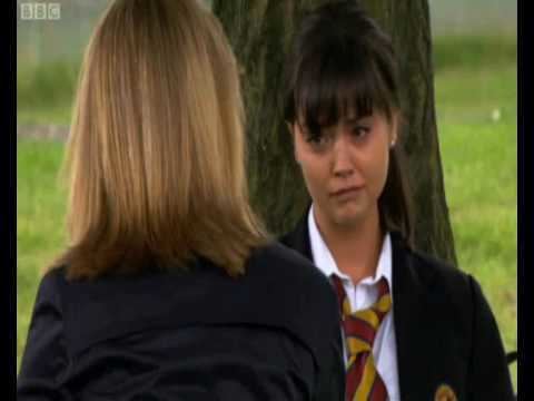 Jenna Coleman as Lindsay James, talking with the woman while wearing a black coat, white long sleeves, and necktie in a scene from the 2006 tv series, Waterloo Road