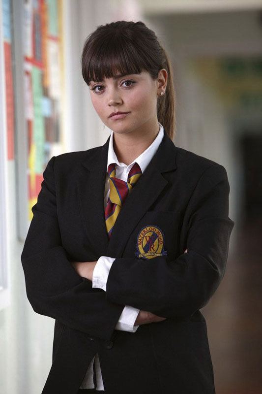 Jenna Coleman as Lindsay James, wearing the Waterloo Road School uniform, a black coat, white long sleeve blouse, and maroon and yellow necktie