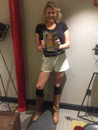 Lindsay Kay Hayward standing near a wall while holding a magazine inside a room