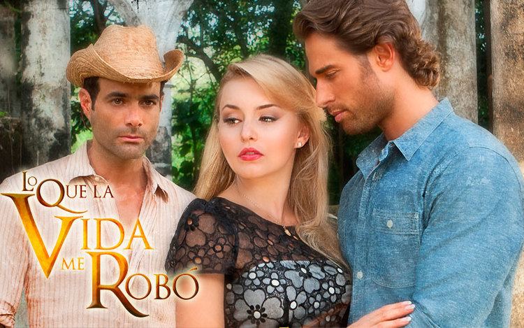 Luis Roberto Guzman, Angelique Boyer, and Sebastián Rulli starring in the 2013 Mexican telenovela, Lo que la vida me robó, with serious faces, Luis is wearing a brown hat and a light orange striped long sleeve. Angelique is wearing a necklace, earrings, and a black and white dress. Sebastian with a beard & mustache is wearing a blue long sleeve